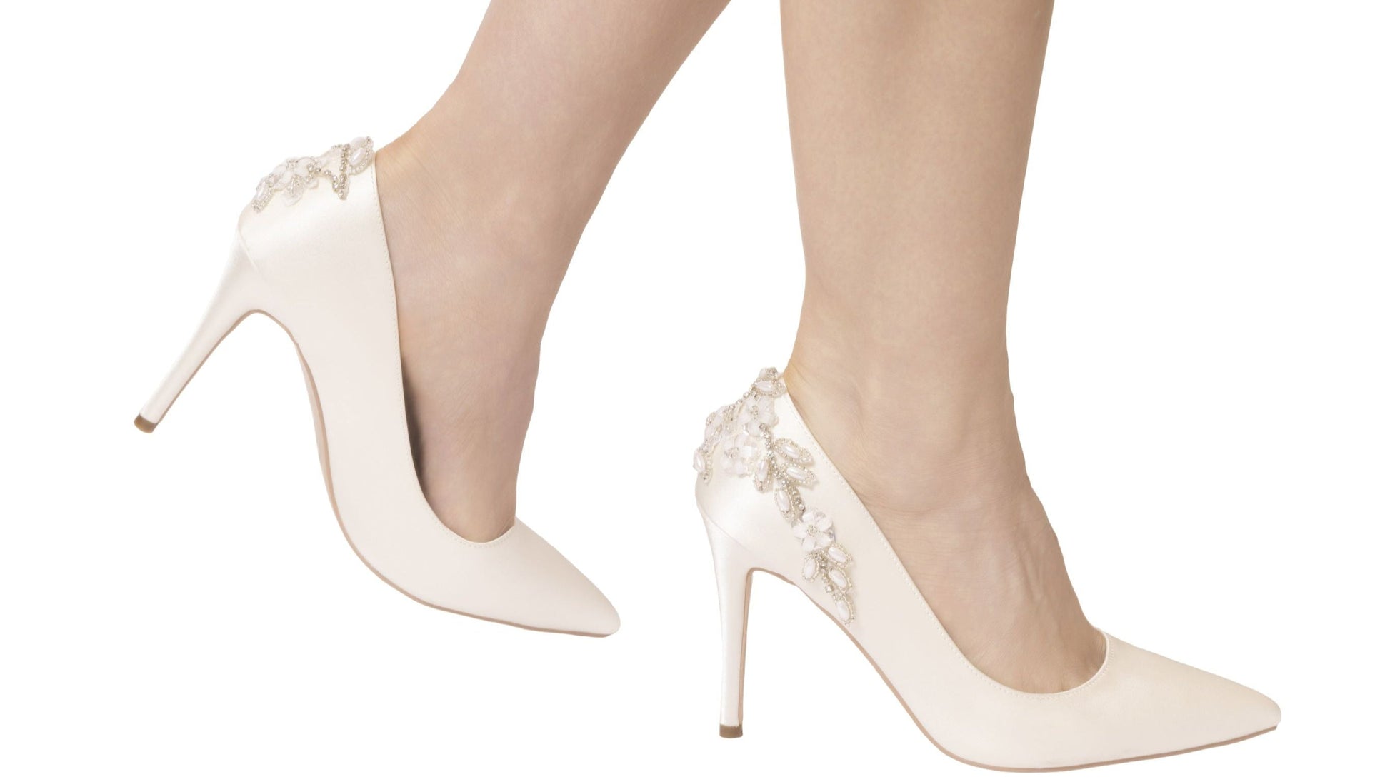 White high-heeled shoes with floral embellishments on a white background